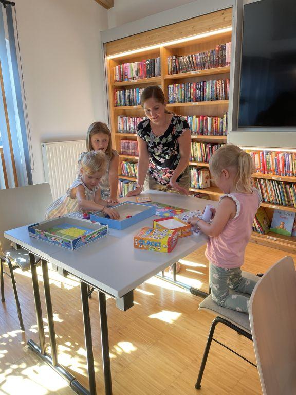 Erwachsene und zwei Mädchen mit Spielen am Tisch