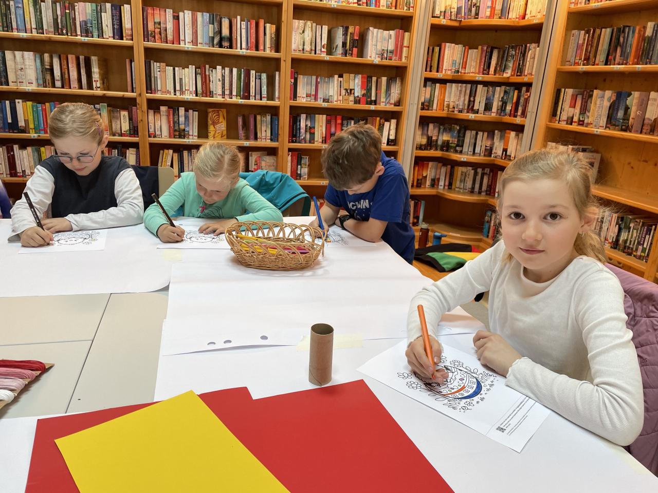 Kinder beim Osterbasteln am Tisch, dahinter Bücherregale